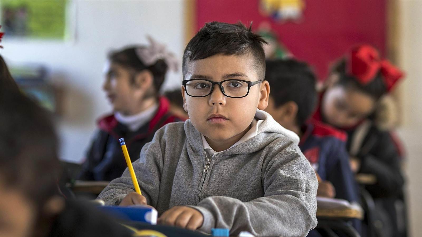 Alumno con lentes y lápiz atento en su sala de clases