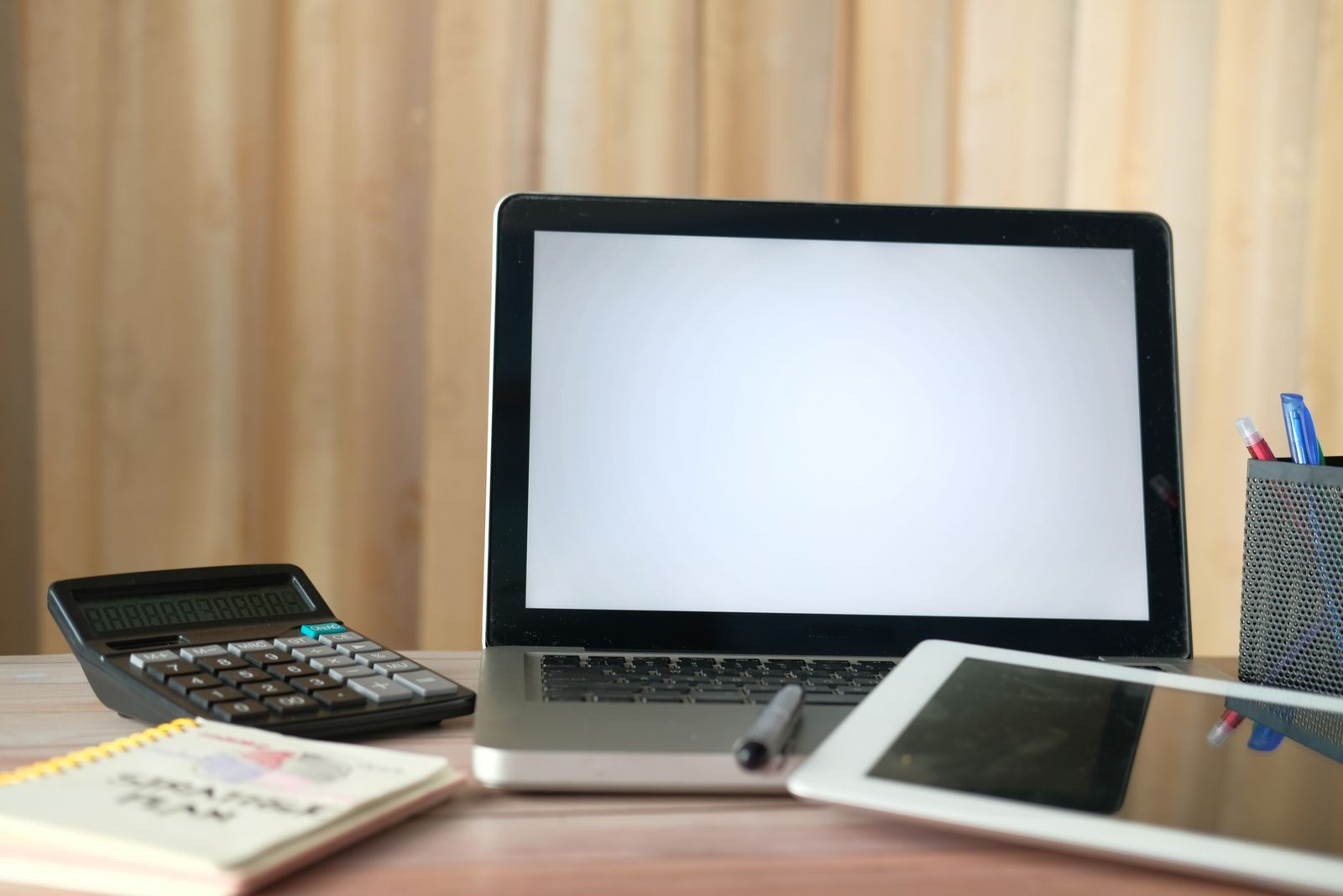 Escritorio con laptop, calculadora, tablet y cuaderno, listo para una clase online