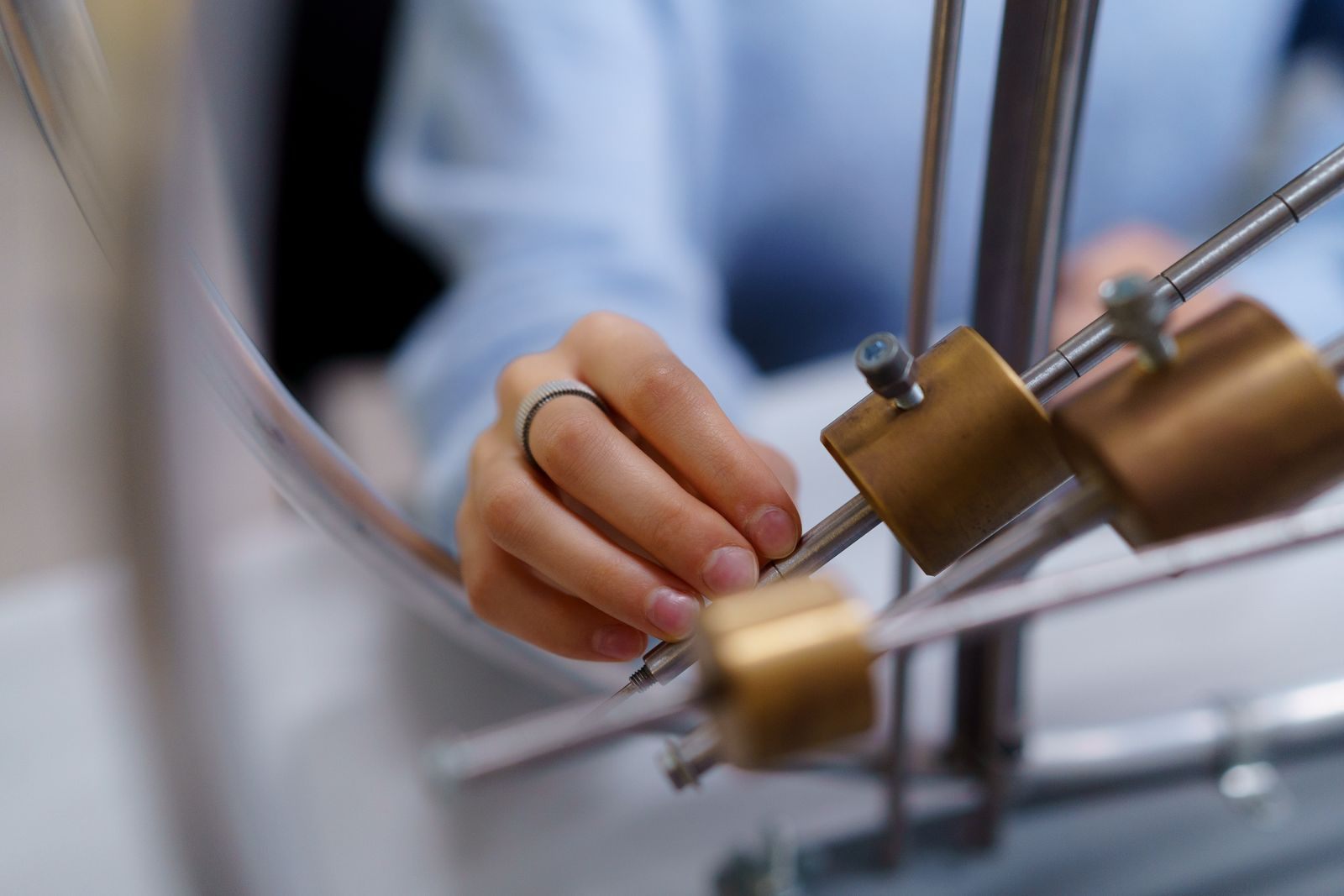 Mano ajustando piezas de latón en un equipo de laboratorio de física