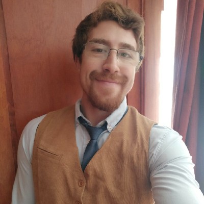 Sergio Vargas sonriendo, con chaleco color caramelo, camisa clara y corbata azul